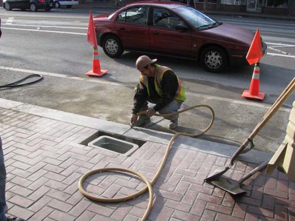 An SFMTA worker installs a counter on Market Street near Van Ness.