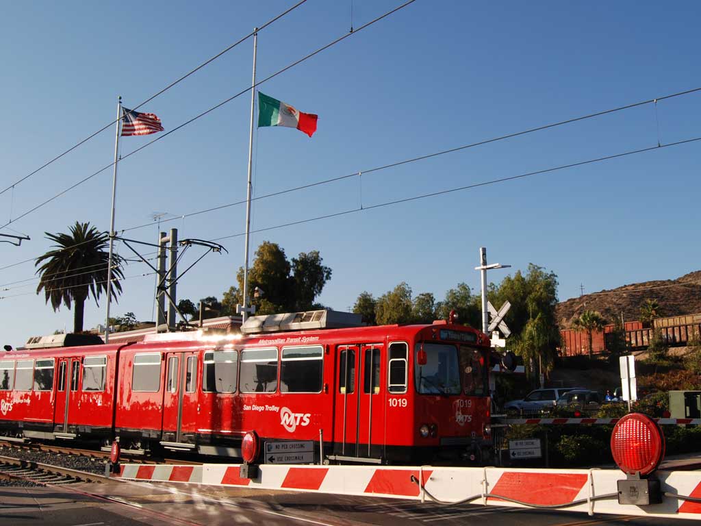 The San Diego Trolley near the Mexican border. Cars are forced to stop at the grade crossing so the train can pass. Wikimedia Commons