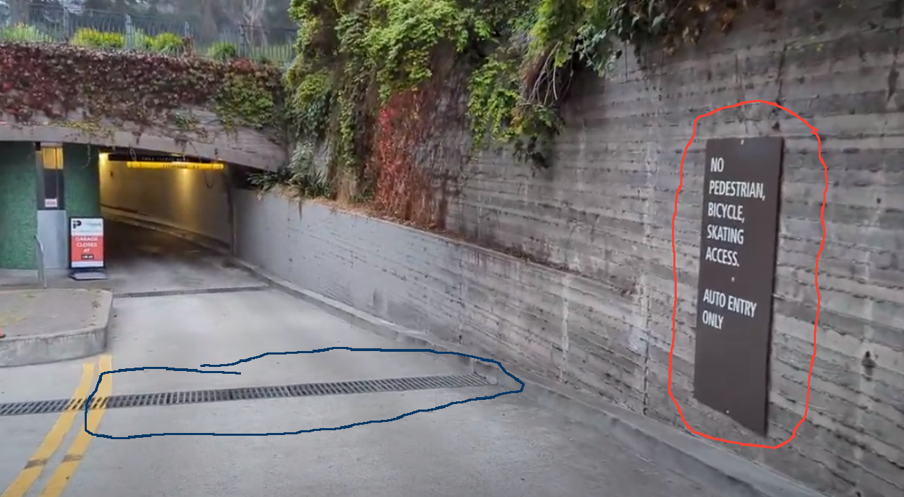 The deadly grate circled in blue. The sign banning bikes circled in red.